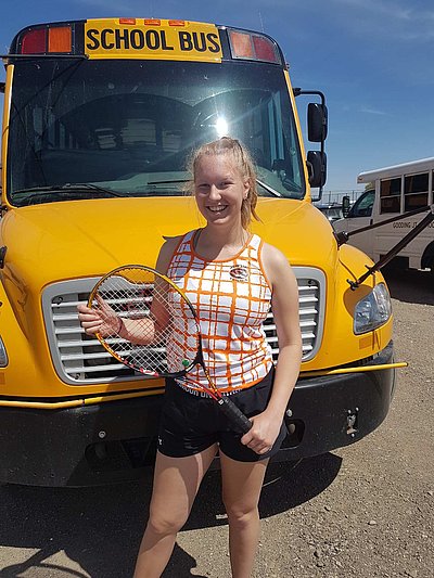 Alicia mit Tennisschläger vor amerikanischem Schulbus